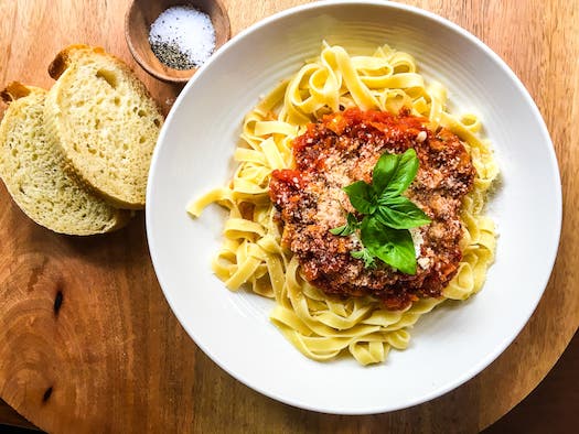 Pasta Meat Sauce on a plate with two slices of bread on the side