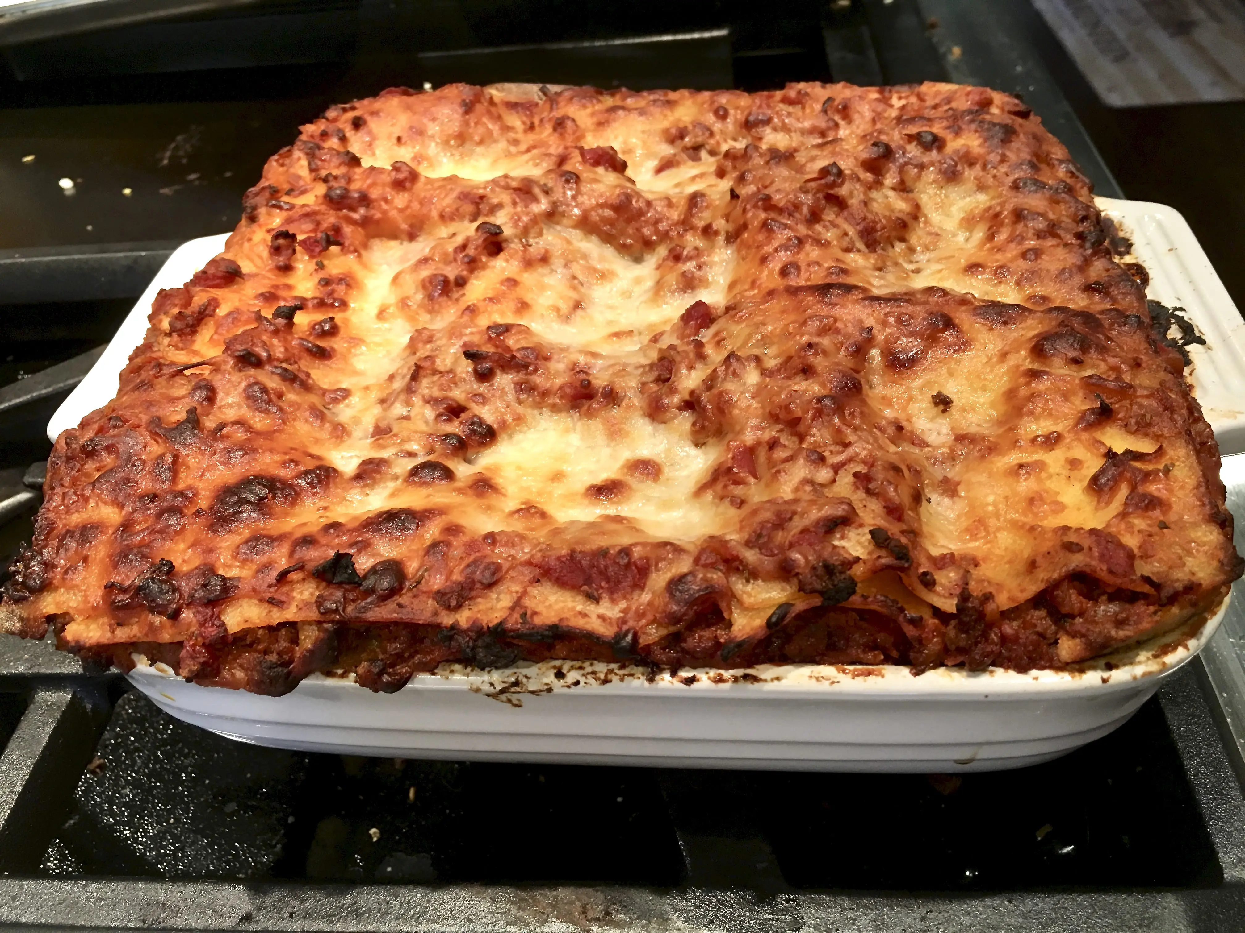 a freshly baked lasagna that's low sodium and gluten-free in a white casserole ready to cut and serve