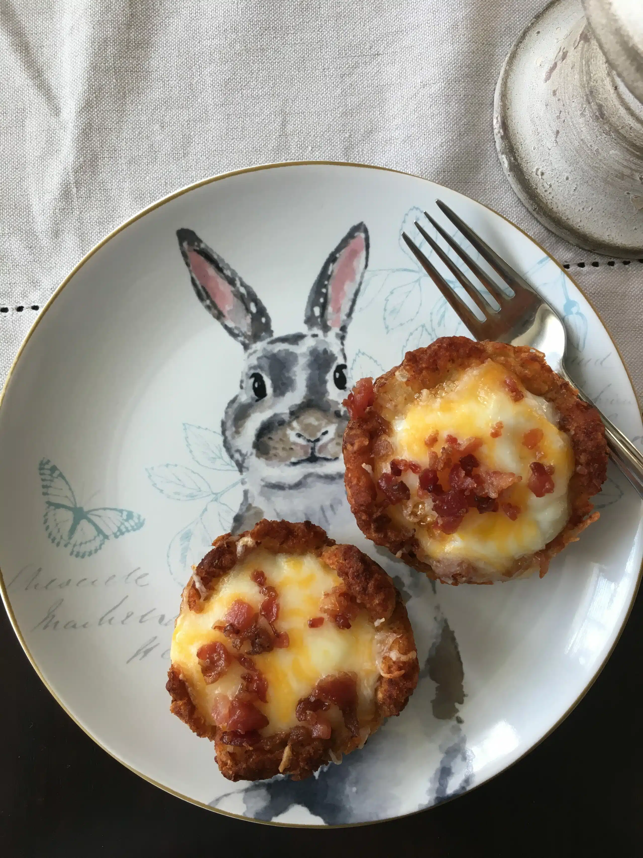 Potato nests with eggs bacon and cheese on a serving plate with a rabbit design.