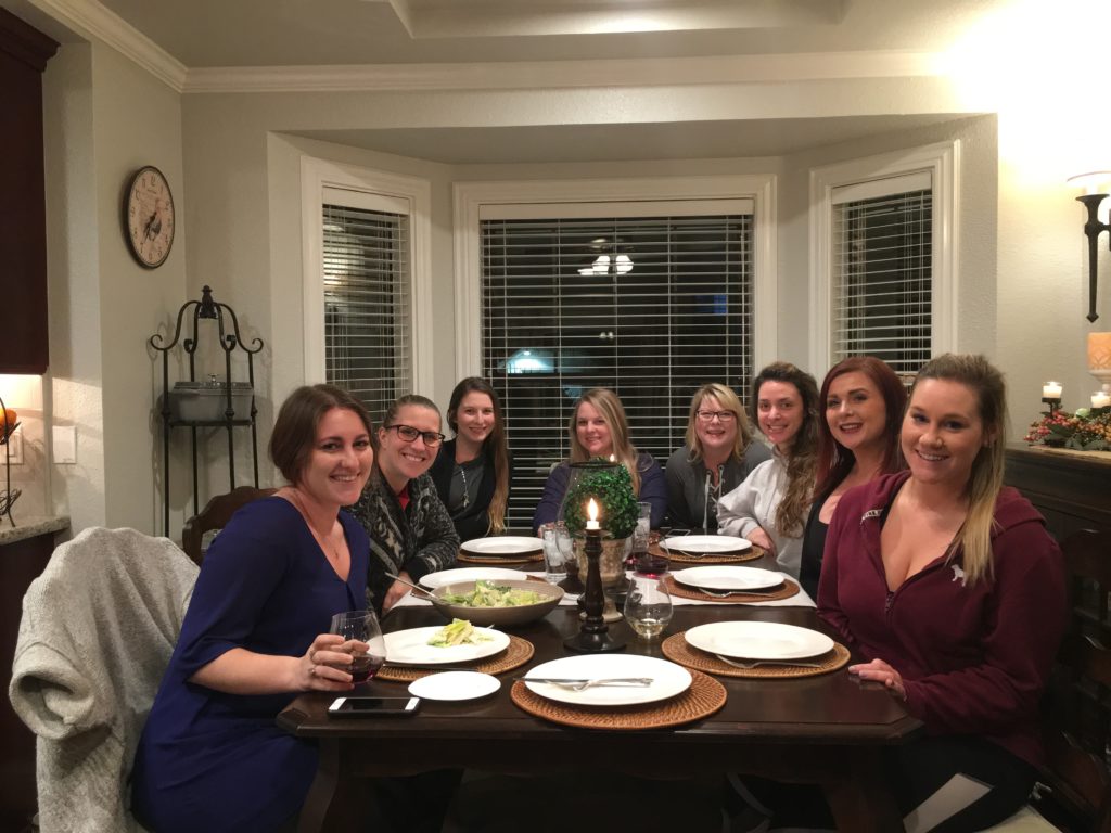 8 girlfriends sitting at a table together on girl's night.