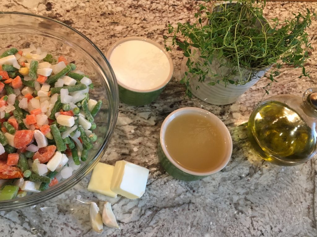 ingredients needed to make chicken pot pie - olive oil, garlic, cheese, milk, chicken broth, vegetables on a bowl