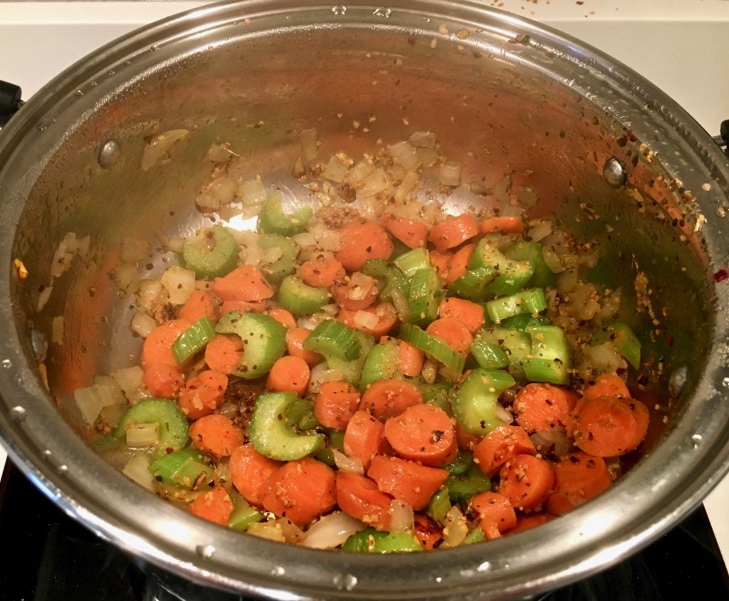Sauté onions, carrots, and celery, before adding the frozen peas, green beans, and flour in a pot