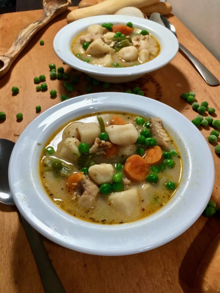two bowls of chicken stew with potato dumplings with vegetables