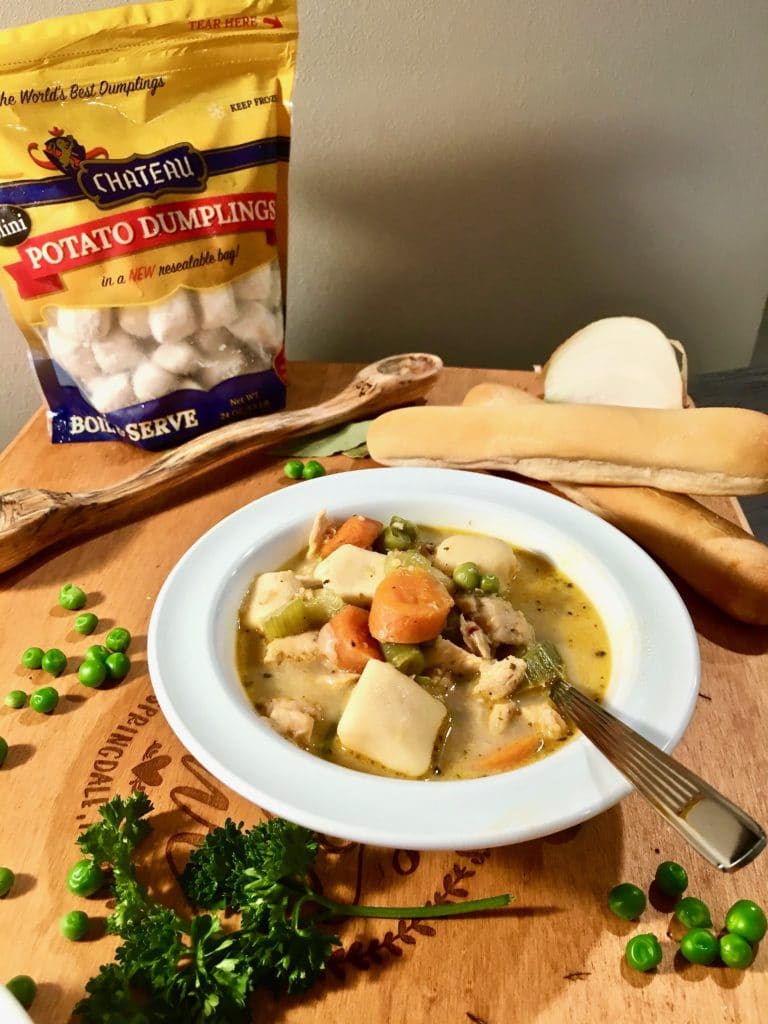 a bowl of Chicken stew with dumplings with a bag of Chateau Dumplings in the background