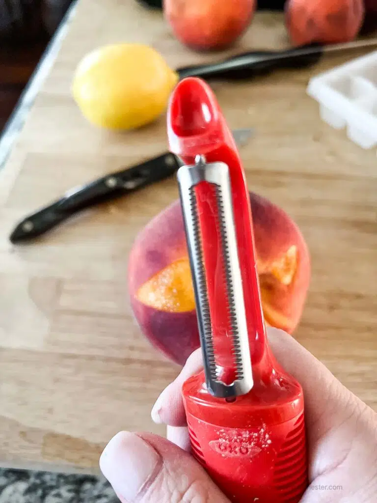 a red serrated peeler for removing peach skin.
