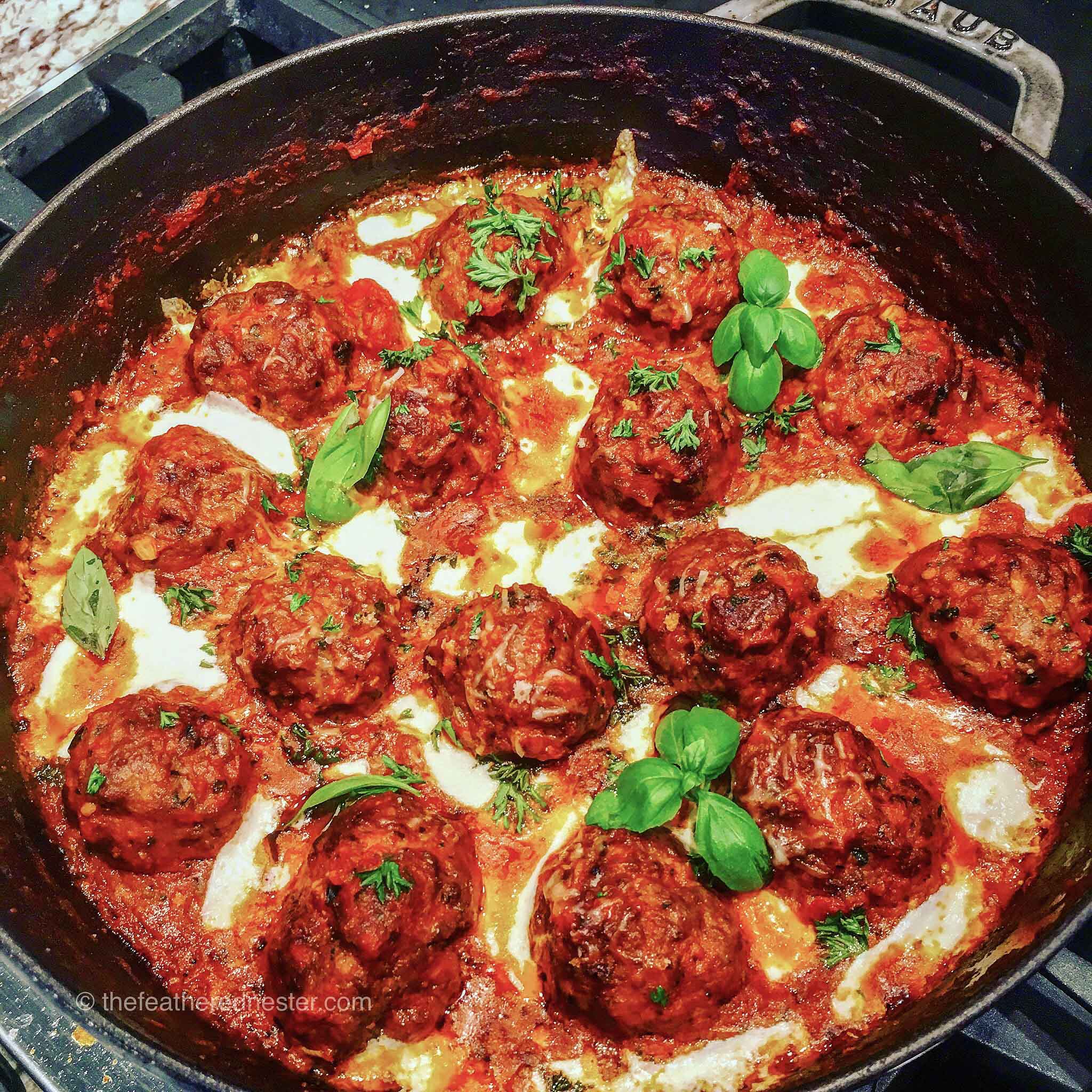 pan fried meatball dinner cooking in a skillet.