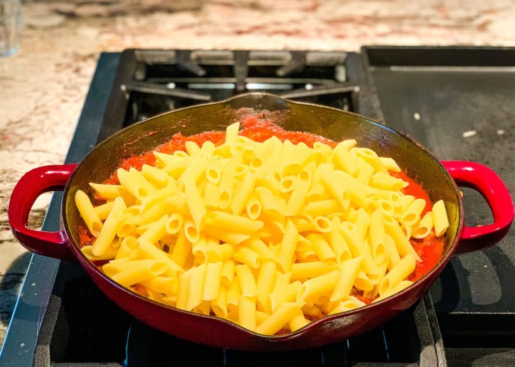 stirring the pasta with the sauce on a pan
