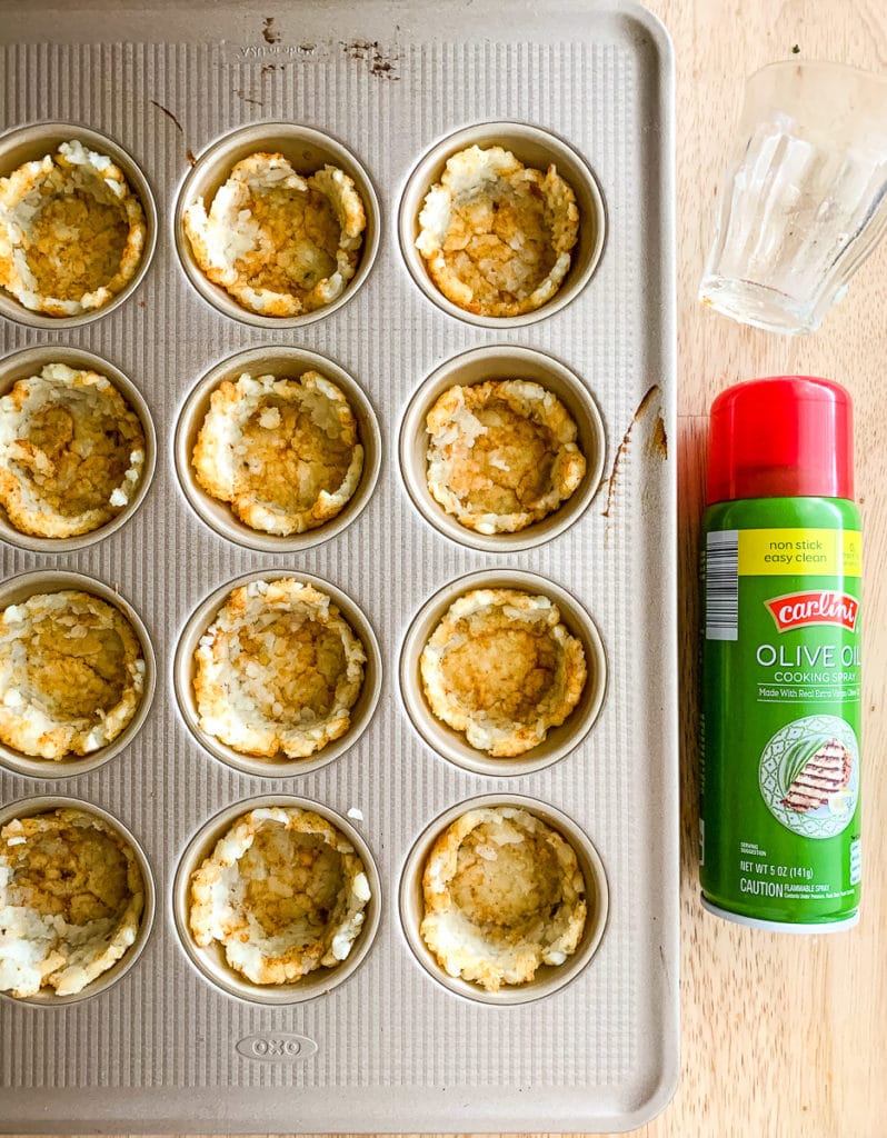 Tater tot cups in the wells of a muffin pan.