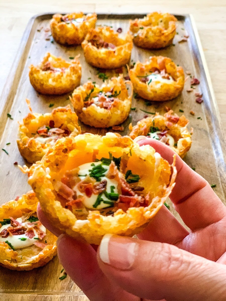 Close up of tater tot appetizer cups filled with bacon, cheese, chives and sour cream.