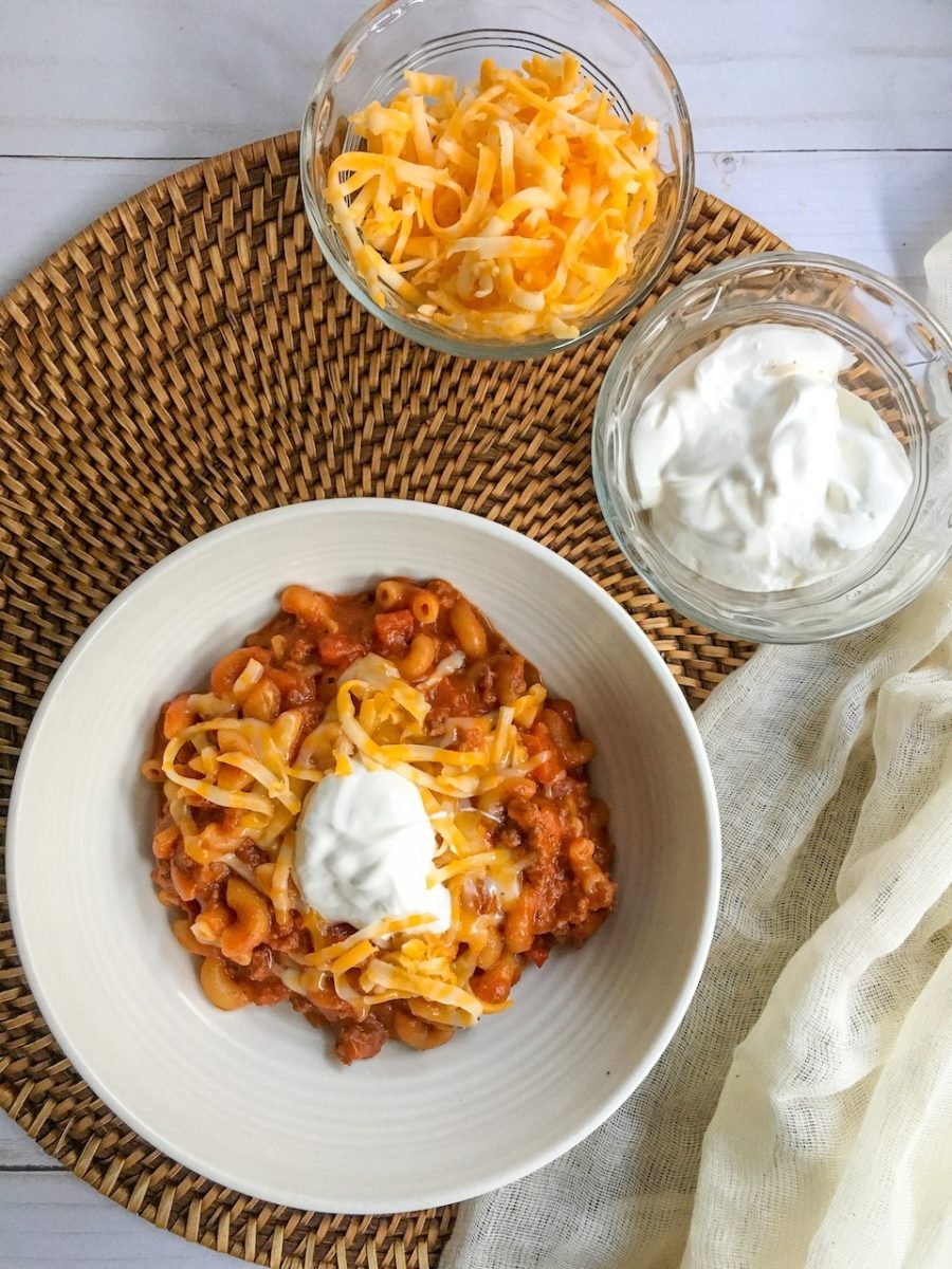 a white bowl of  Chili Cheese Mac topped with sour cream