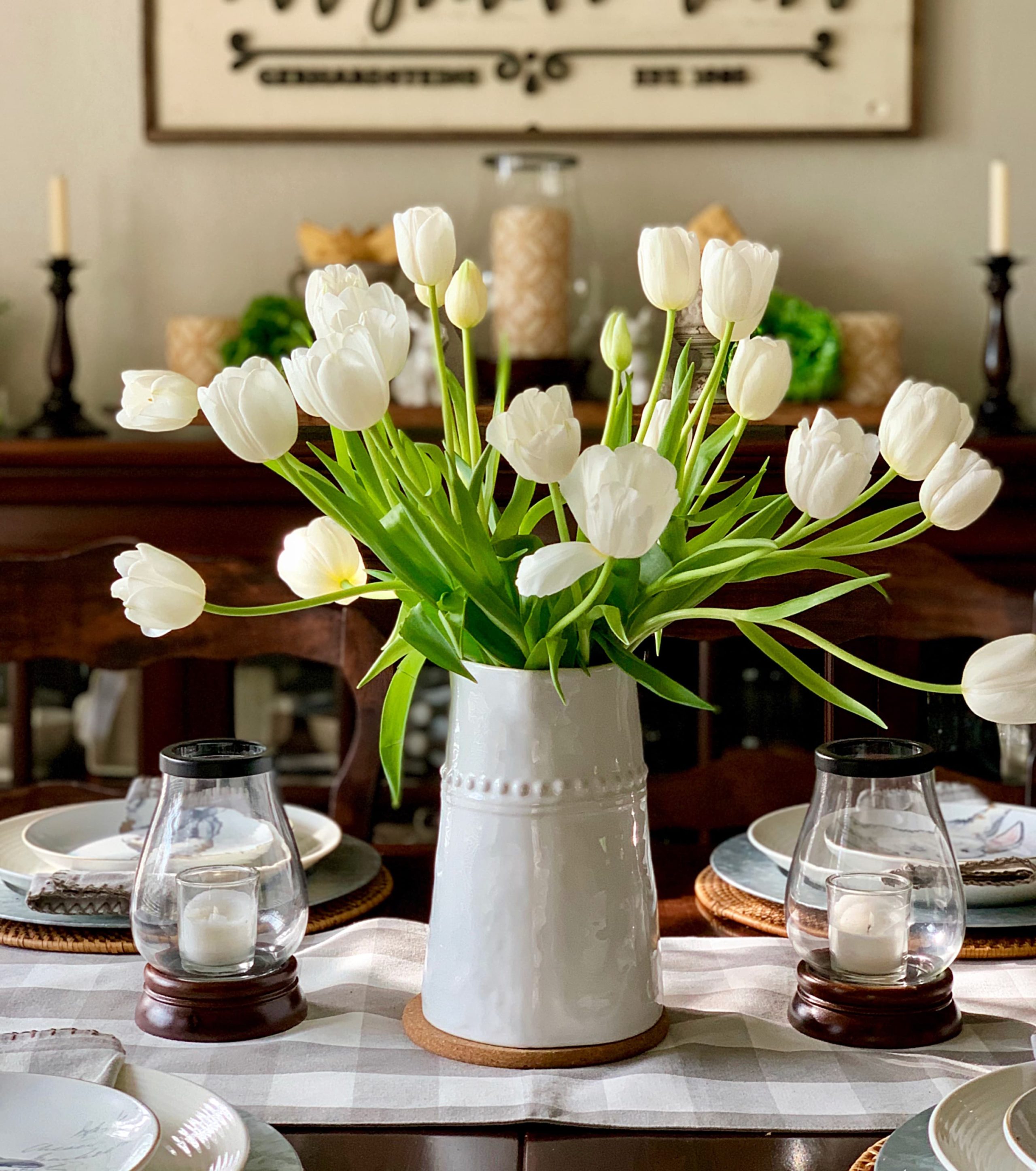 lots of white tulips on a white vase.