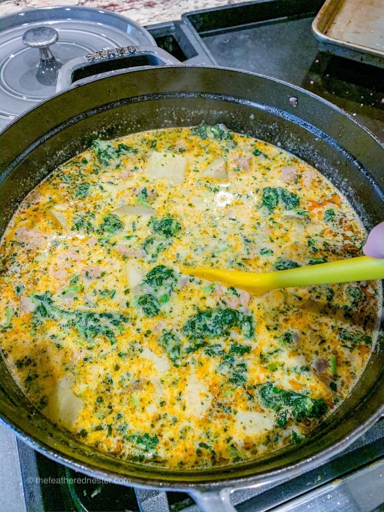a cast iron pot of potato sausage kale soup aka Zuppa Toscana Soup.
