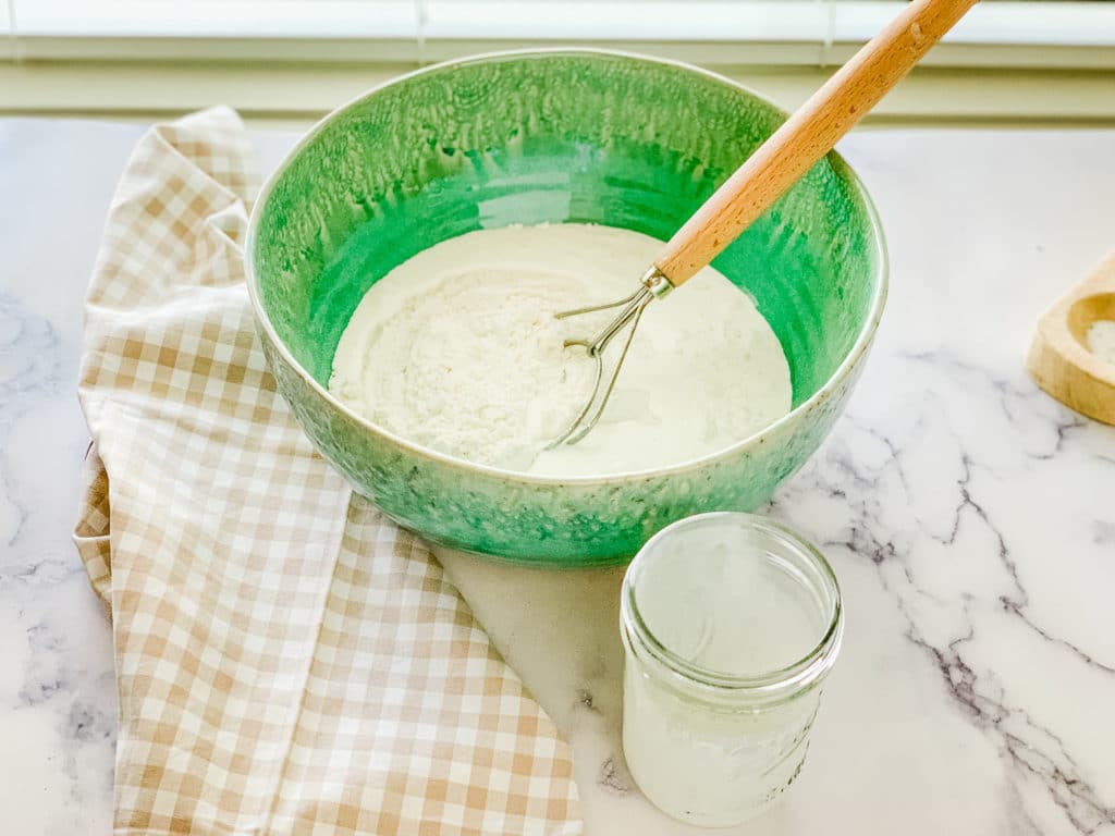 Mixing bowl with self rising flour mixed with heavy cream for easy homemade biscuits