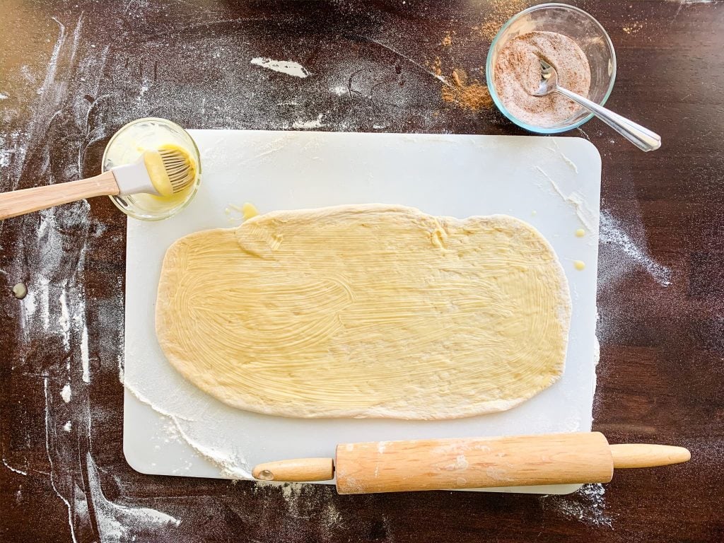 brushing butter on the pumpkin spice bread dough