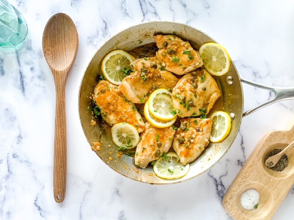 Homemade version of chicken piccata Cheesecake Factory recipe (shown in a large skillet garnished with lemon slices).