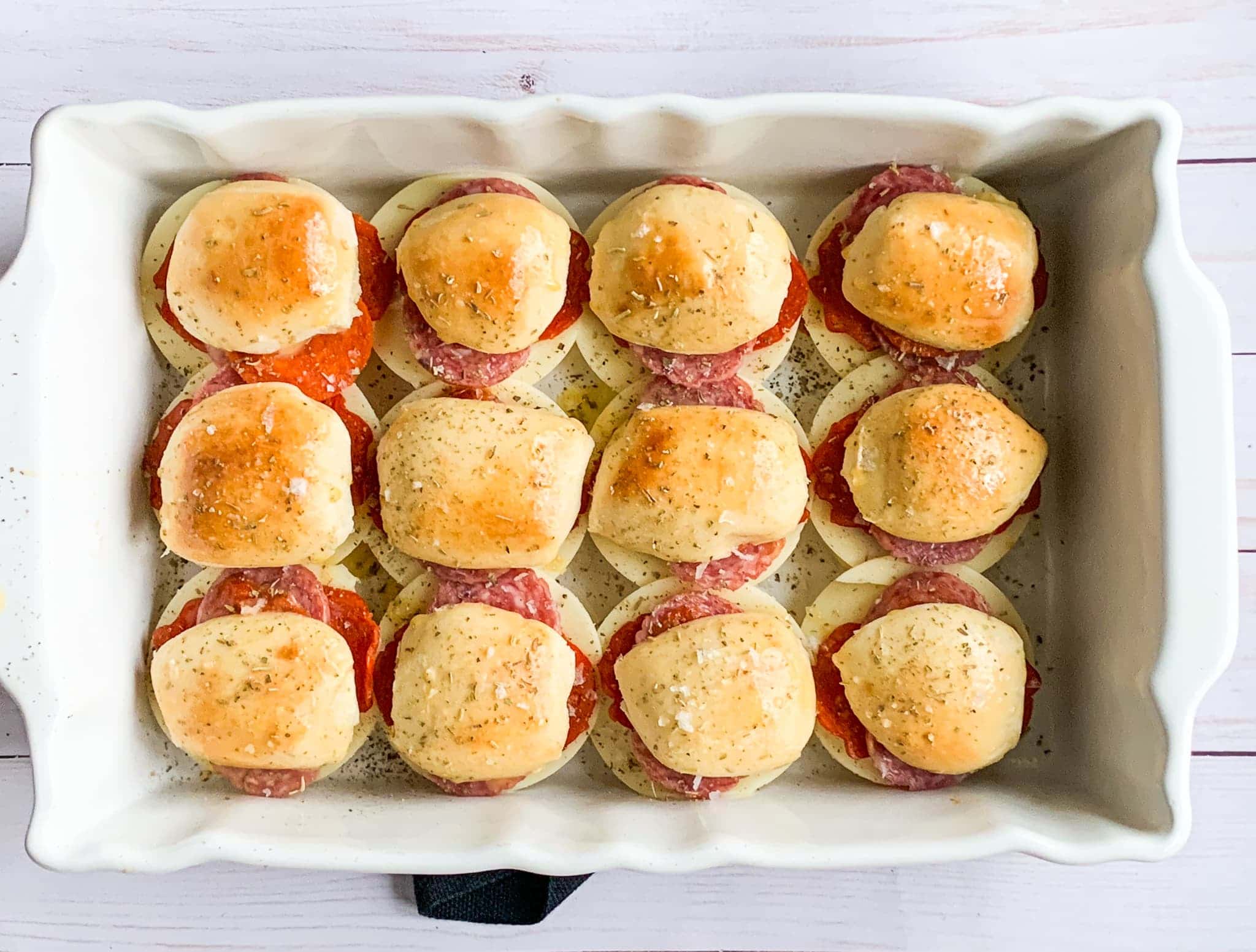 A rectangular baking dish with italian sliders