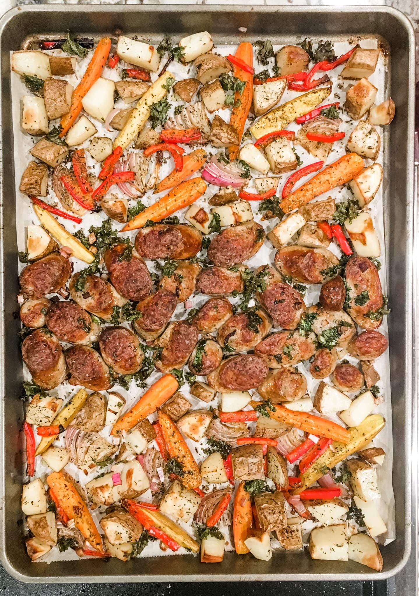 a sheet pan of sausage and sliced vegetables.