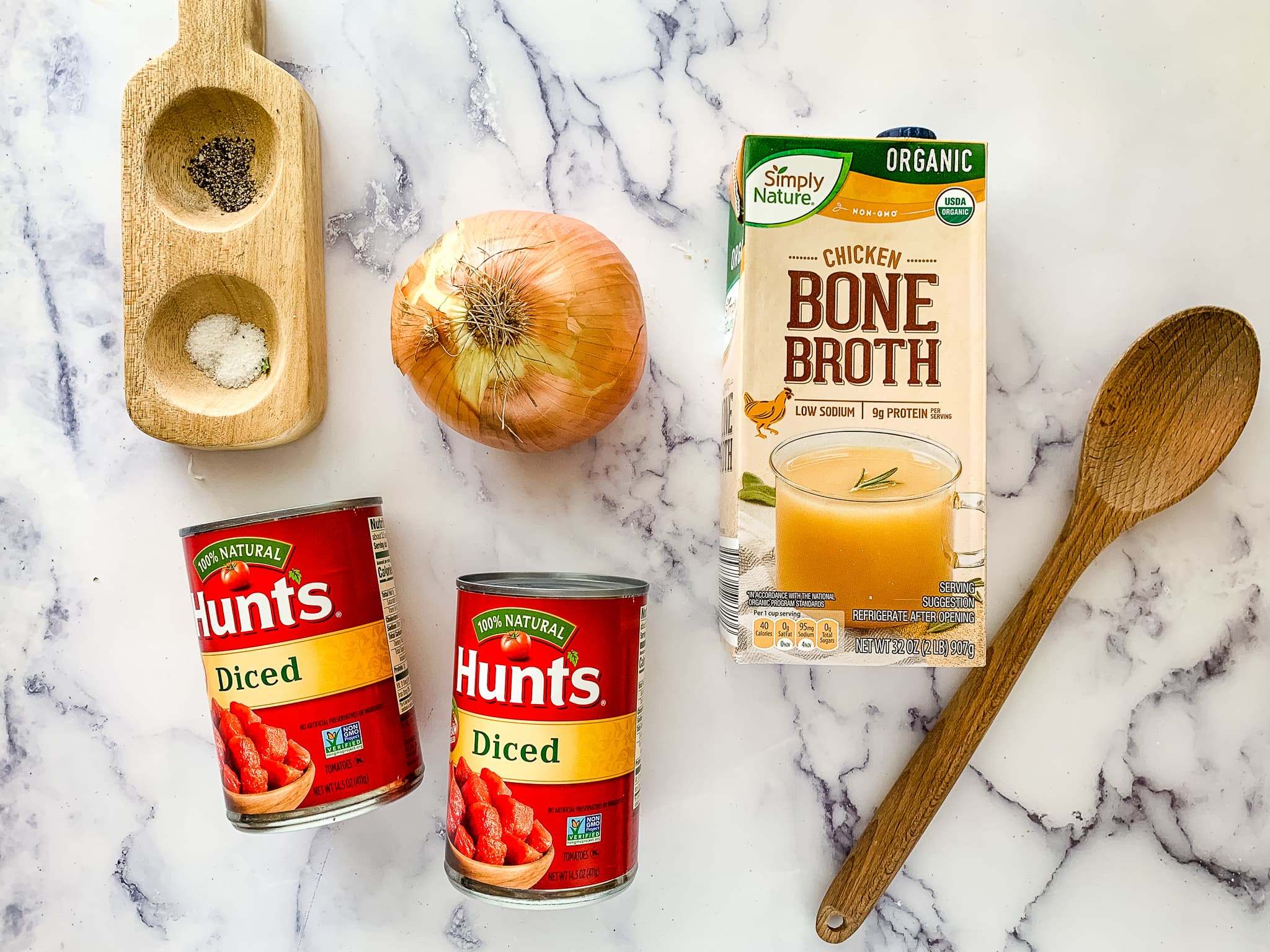 Hunts diced tomatoes, an onion, and Simply Nature chicken bone broth and a wooden spoon.