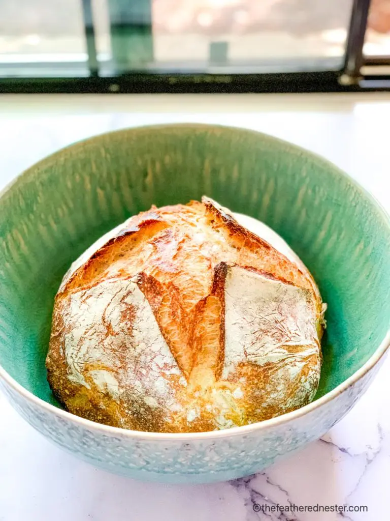 green bowl with a loaf of no knead sourdough bread