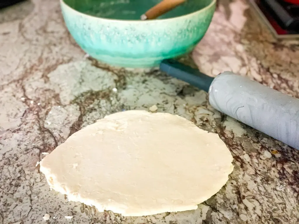 A photo of Easy 3 Ingredient Biscuits dough ready to be cut into biscuits. In the background is a mixing bowl.