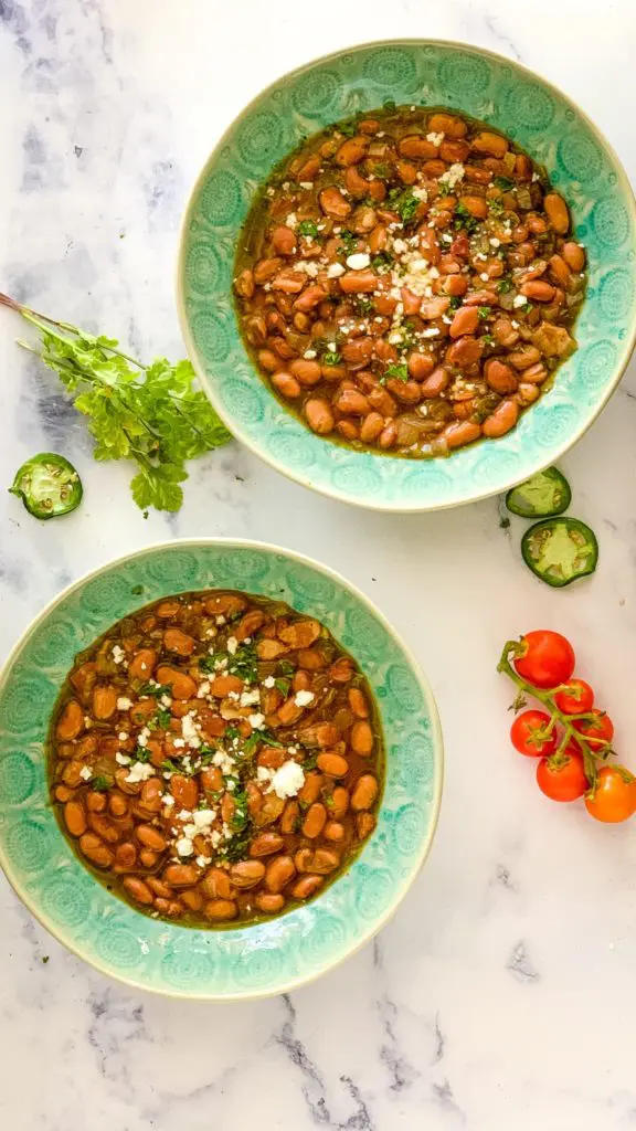 two green bowls of pinto beans made from the ultimate pinto beans recipe