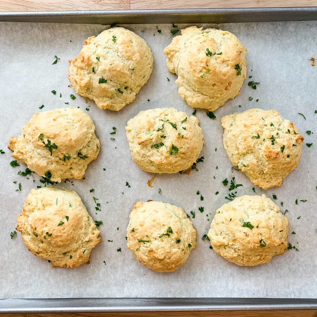 Baked bread rolls on a parchment lined sheet pan.