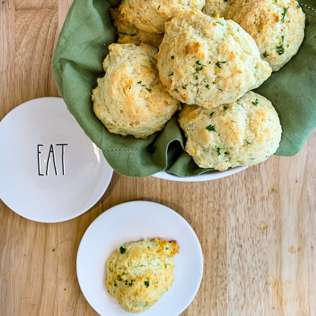 Jalapeno biscuits in a basket. One half eaten drop biscuit on a plate in front of the basket.