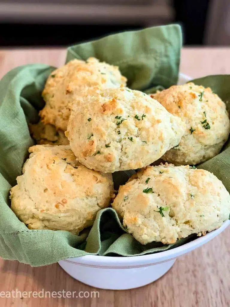 a basket of jalapeno cheddar biscuits in a white bowl lined with a green napkin.