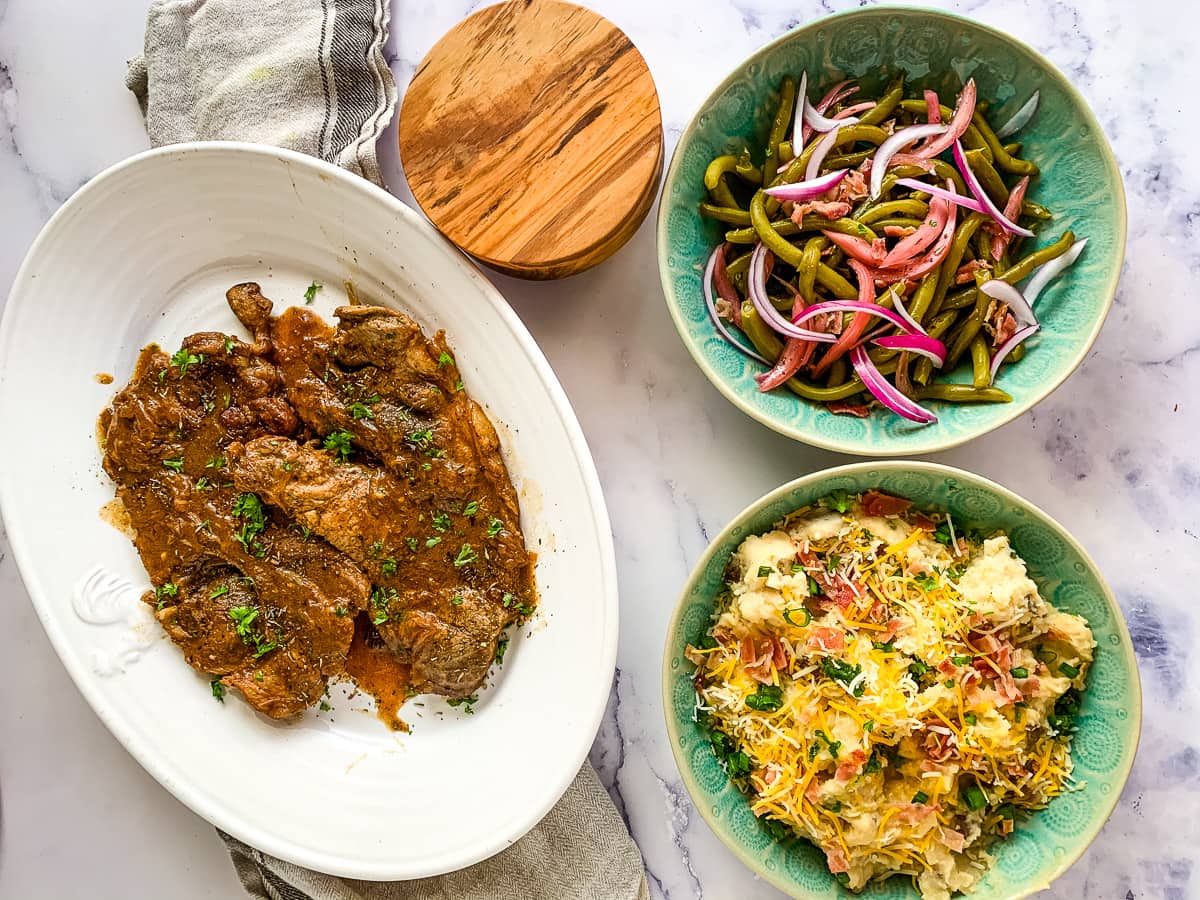 Instant Pot Pork Chops shown with a smaller serving bowl of Instant Pot Loaded Potatoes.