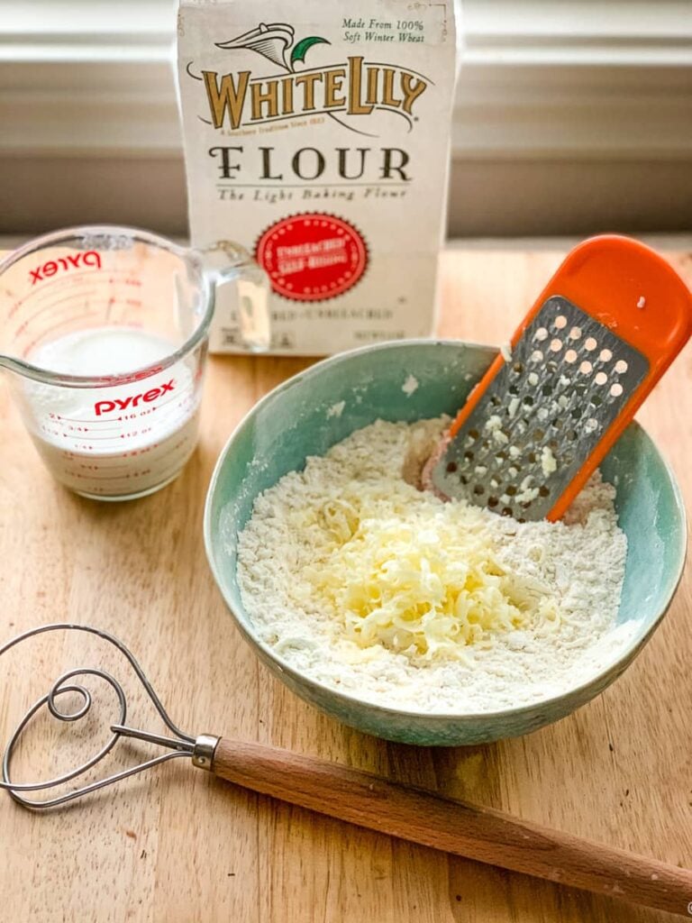 Grating cold butter into a bowl of flour.