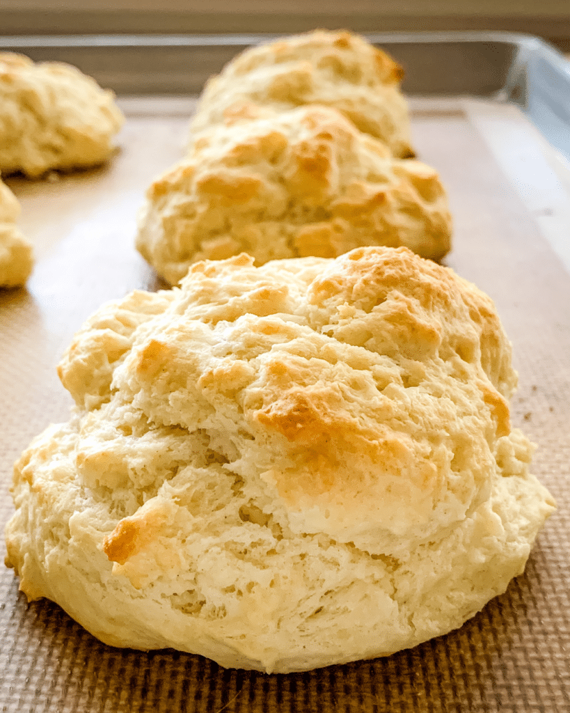 Close up of a freshly baked drop biscuit on a baking pan.