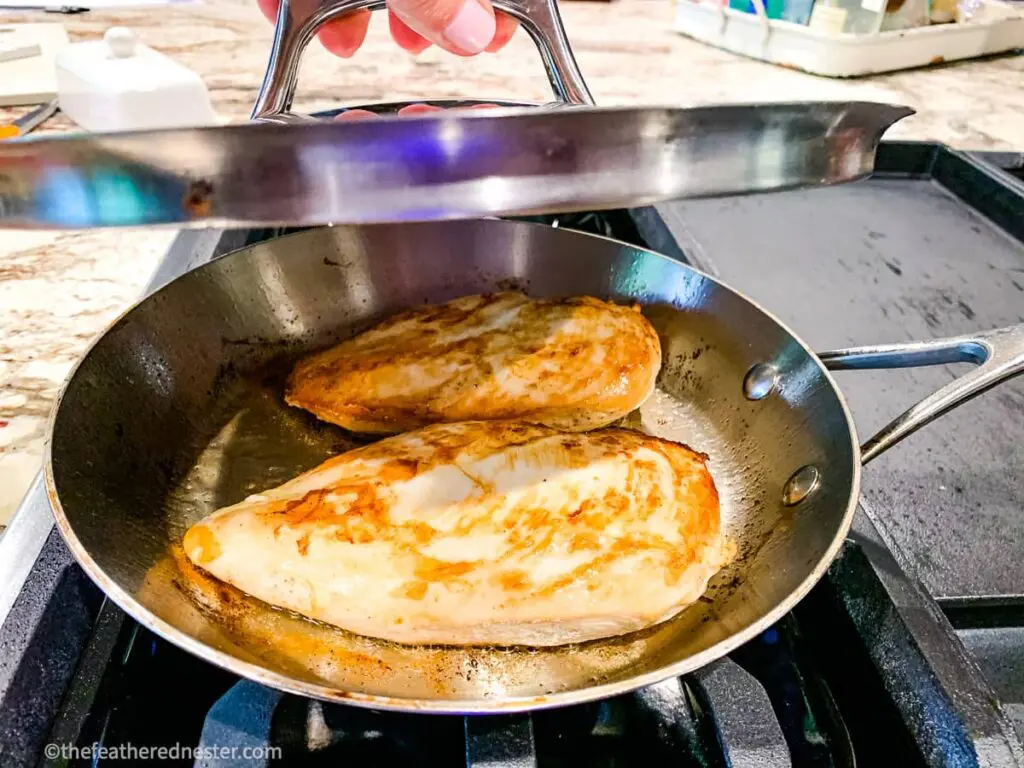 Placing a lid over a skillet of pan seared chicken