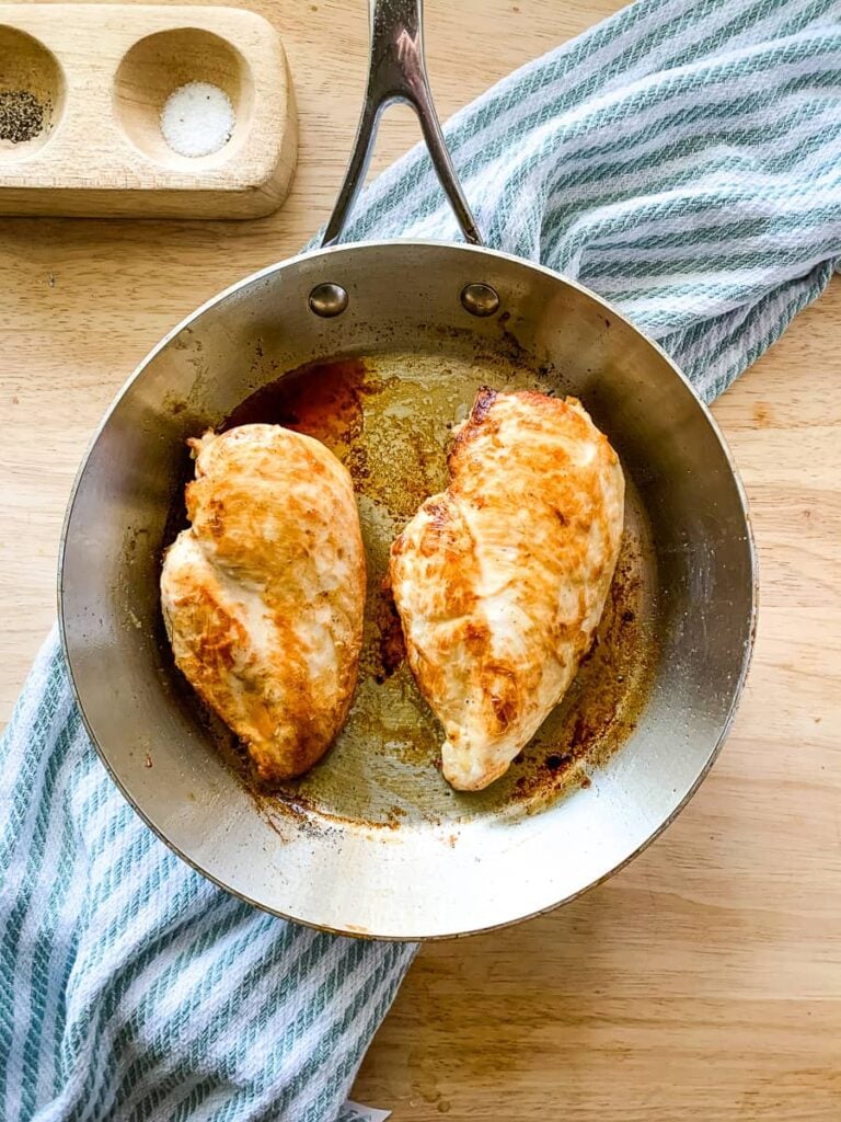 A stainless steel skillet with pan seared chicken breasts