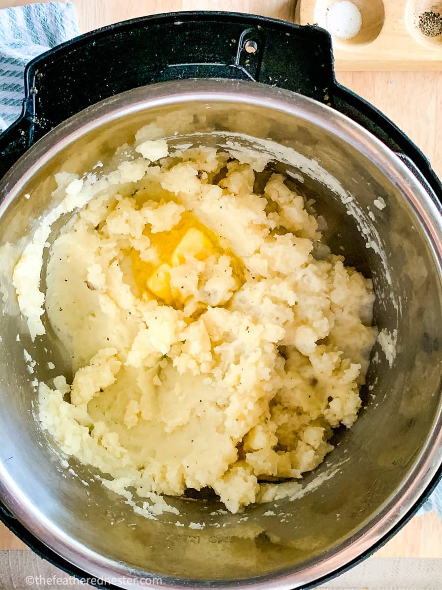 Instant Pot mashed potatoes with butter melting over them in the pressure cooker.