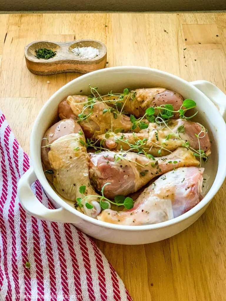 a bowl with balsamic marinated drumsticks ready to bake on a sheet pan