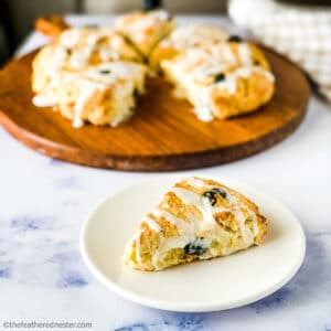 a plate with cranberry almond scone and a wooden board with scones on it.