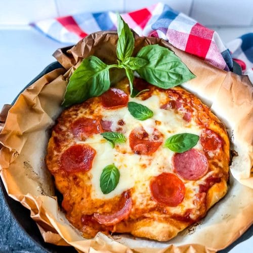 a cast iron skillet with a pizza in it.