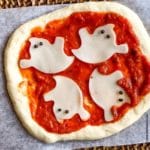a mini ghost halloween pizza on parchment paper ready to bake