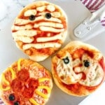 three halloween pizzas: mummy pizza, ghost pizza, spider pizza.