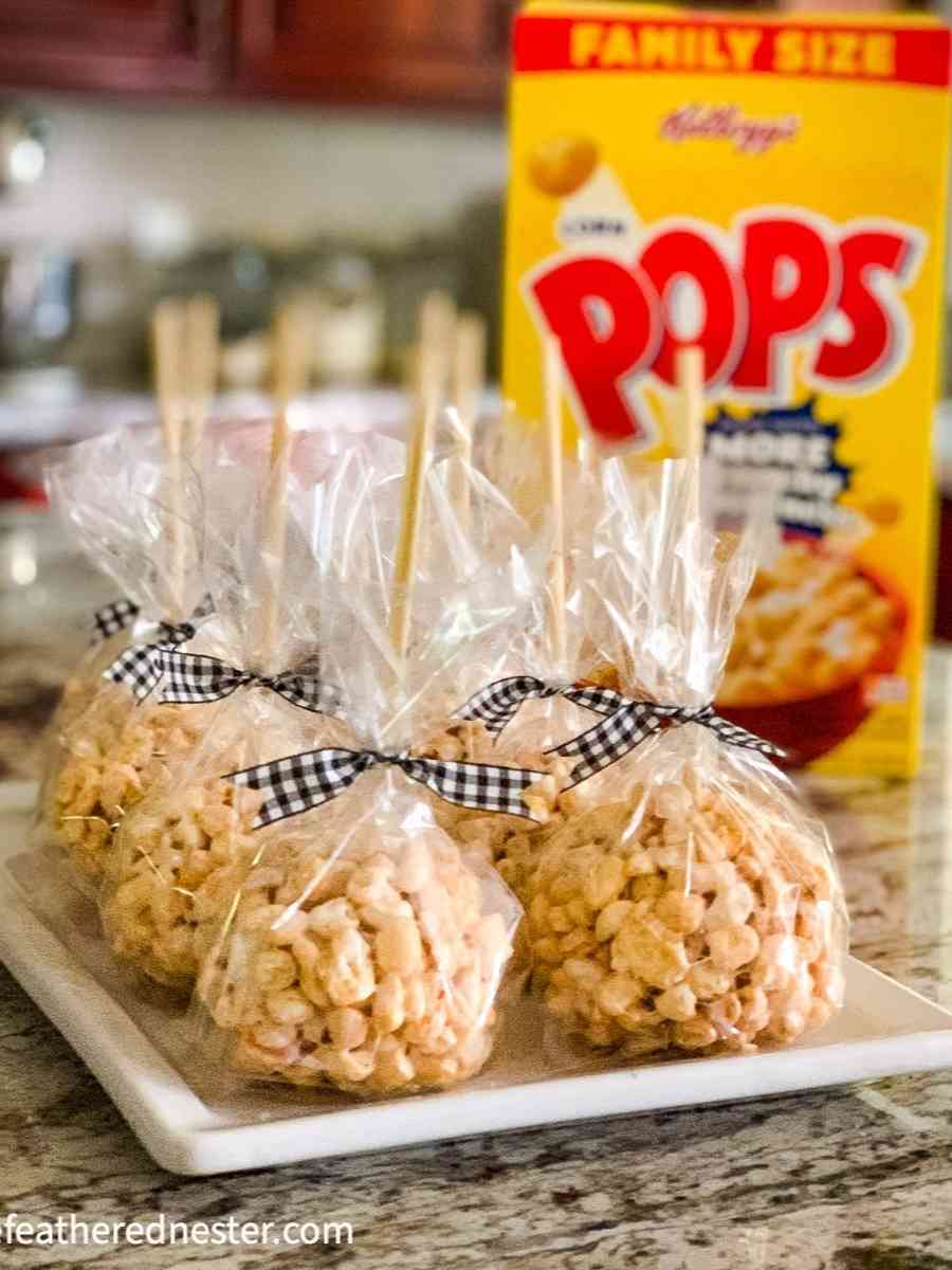a platter of cellophane wrapped corn pop treats tied with black and white ribbon and a box of Corn Pops cereal in the background.