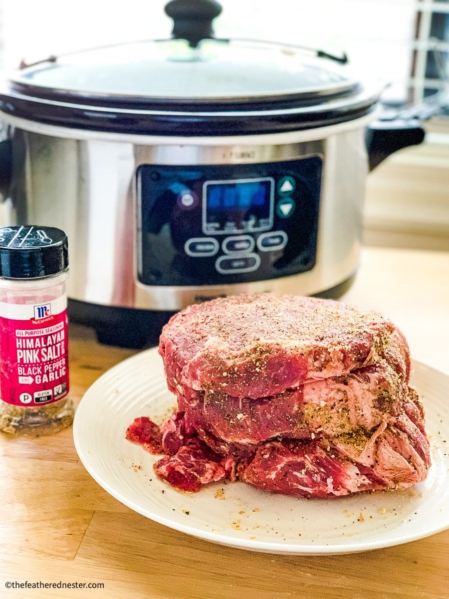 seasoned beef roast with a crock pot and McCormick all purpose seasoning in the background