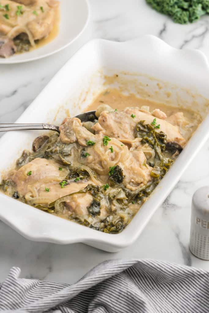 a white casserole serving dish with smothered chicken
