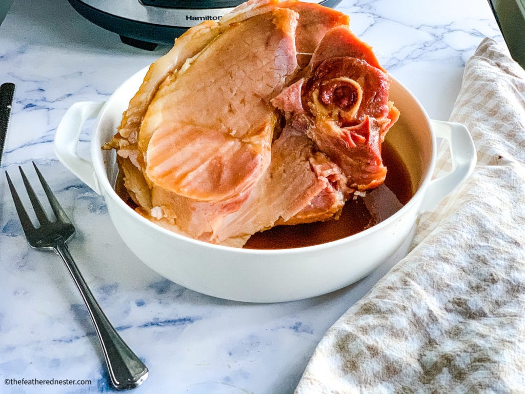 Coca Cola crock pot ham with pineapple glaze in a white dish.