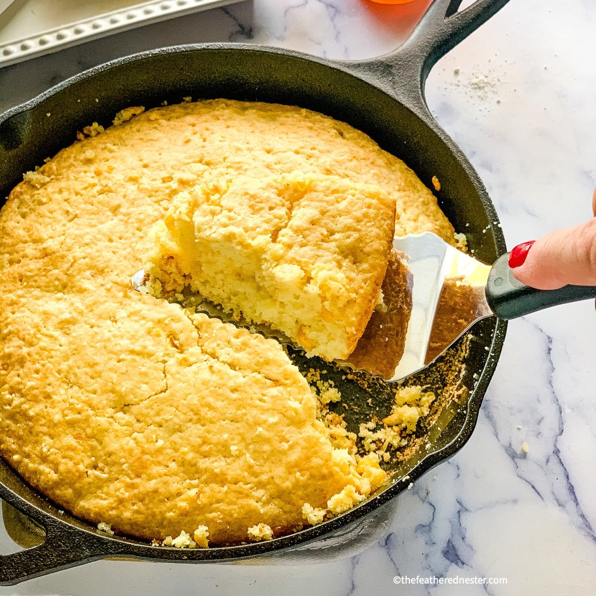 slice of Bisquick corn bread on a spatula above cast iron skillet.