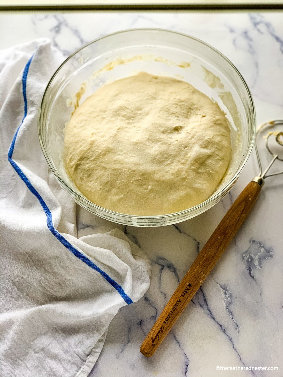 a bowl of fermented sourdough bread dough in a clear glass bowl.