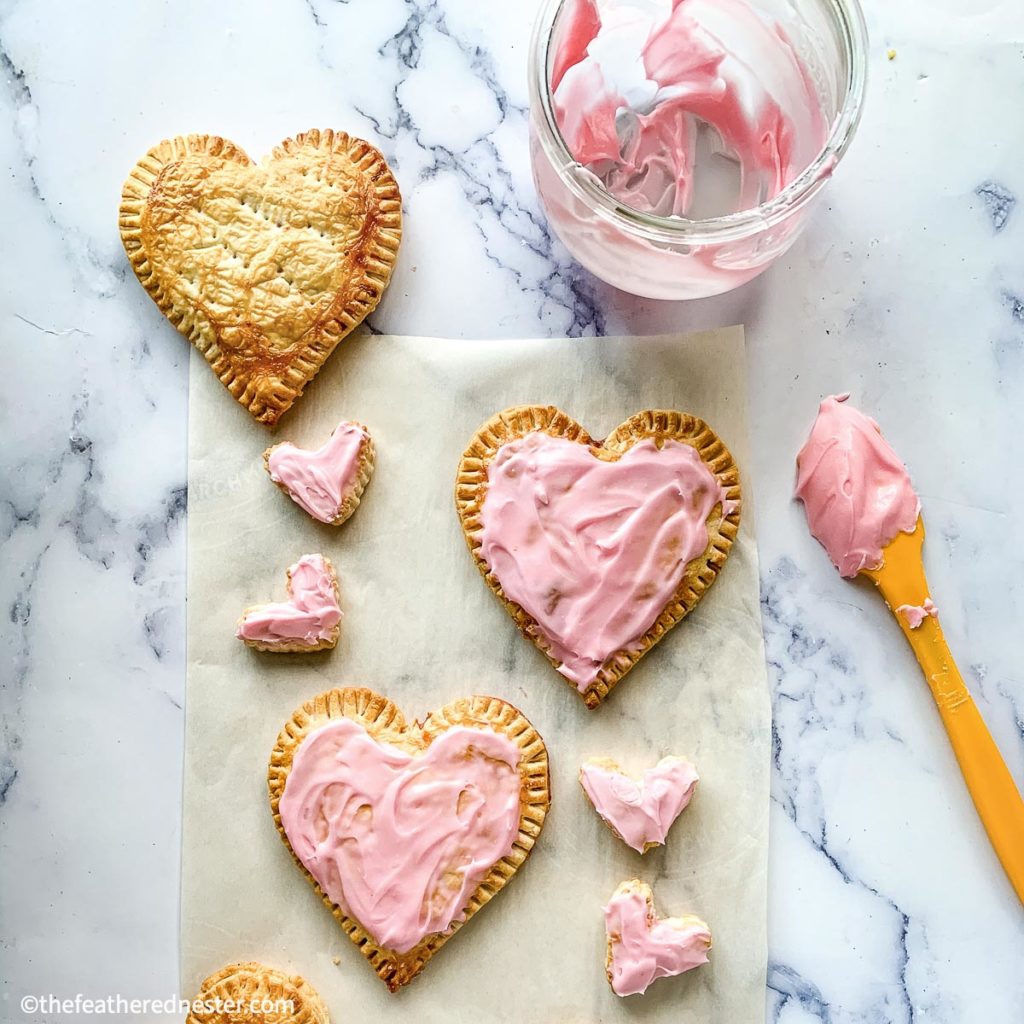 A heart-shaped treats on a baking tissue paper with a jam on top
