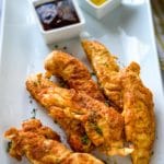 a plate of Instant Pot Chicken Tenders with honey mustard and barbecue dipping sauces.