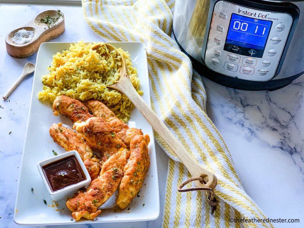 Platter of cooked tenderloin strips with rice and bowls of dipping sauces, next to an instant pot.