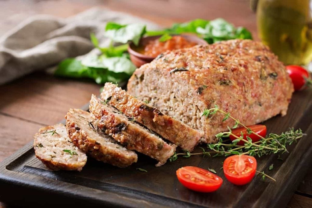 Sliced turkey meatloaf placed on a cutting board.