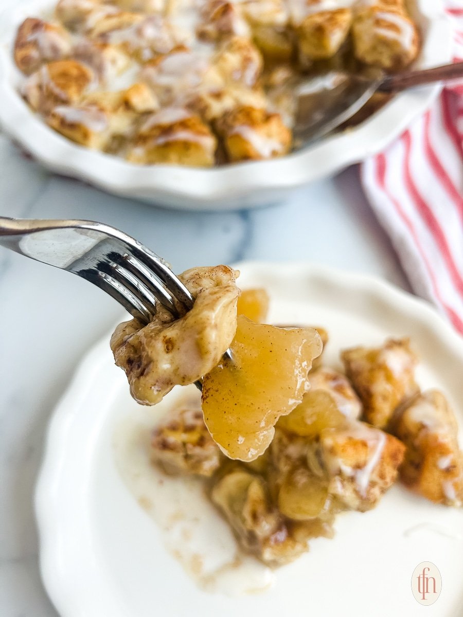 Closeup of cinnamon rolls on a fork over a white plate. 